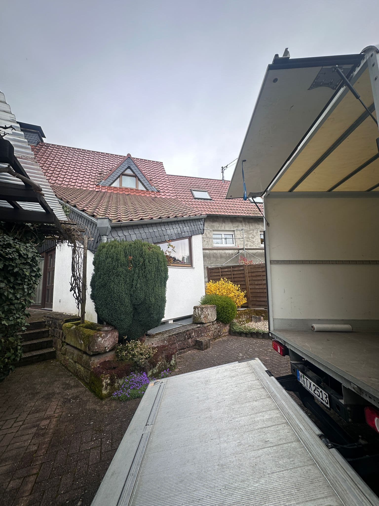 Umzugswagen mit heruntergelassener Ladebordwand vor einem Wohnhaus